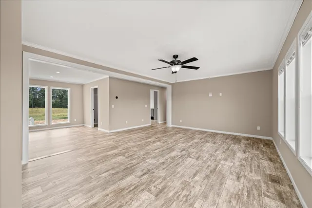 a view of an empty room with a window and wooden floor