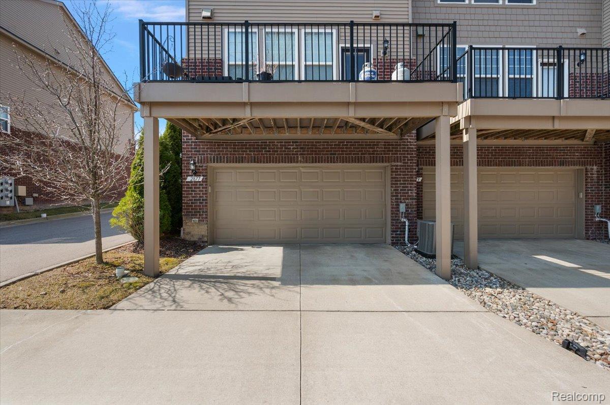 2877 Hartwick Drive Rochester, MI 48307 - Photo 5 of 44 View of front of home featuring concrete driveway, brick siding, a balcony, and a garage