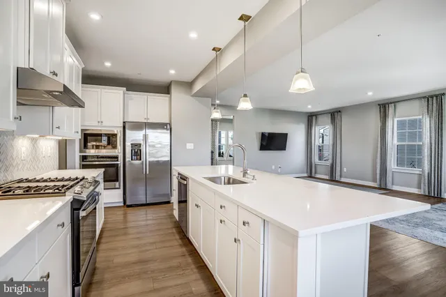 a large kitchen with stainless steel appliances kitchen island a large counter tops and white cabinets
