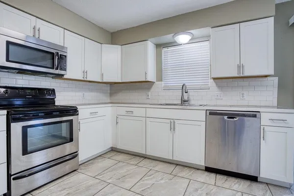 a kitchen with stainless steel appliances granite countertop grey cabinets and a stove a oven