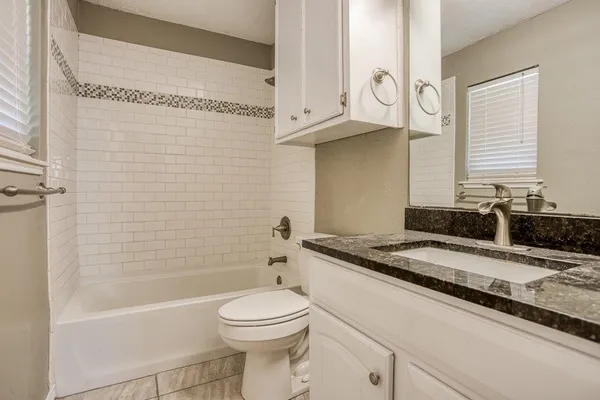 a bathroom with a granite countertop sink and a toilet