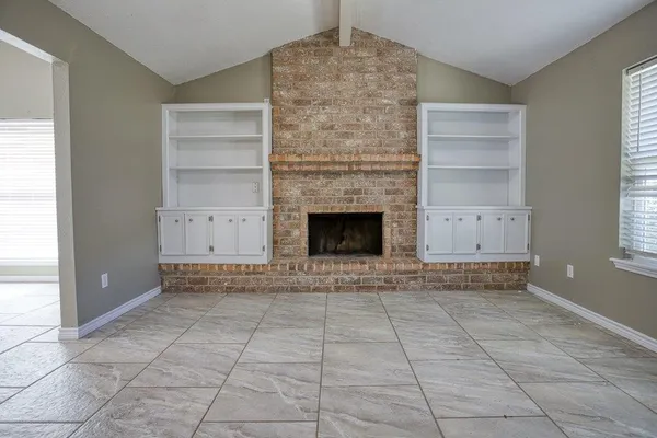 an empty room with windows and fireplace