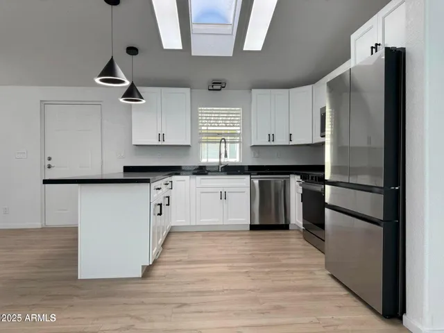a kitchen with granite countertop a refrigerator and a stove top oven