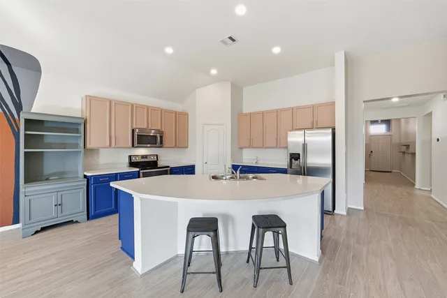 a large kitchen with cabinets wooden floor and stainless steel appliances