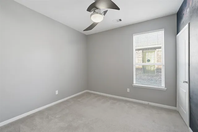 an empty room with a window and a fan