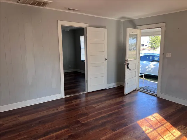 a view of an empty room with wooden floor and a window