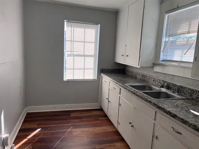 a kitchen with granite countertop white cabinets and a sink