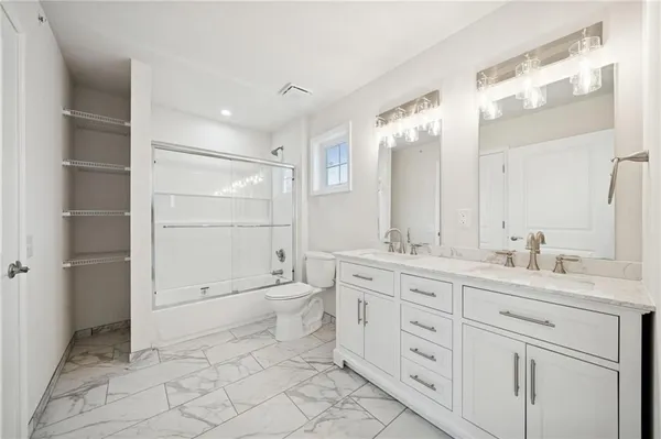 a spacious bathroom with a granite countertop sink a toilet and a mirror