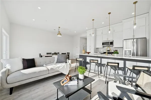 a living room with furniture kitchen and a wooden floor