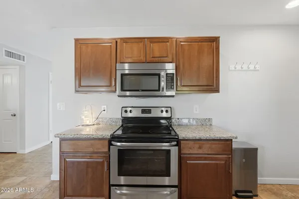 a kitchen with granite countertop a stove top oven microwave and cabinets