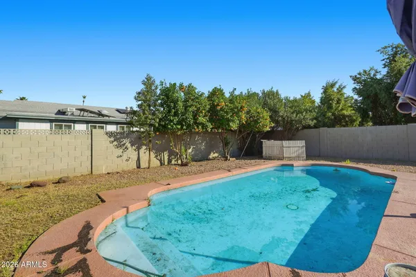 a balcony with a table and chairs under an umbrella with large trees