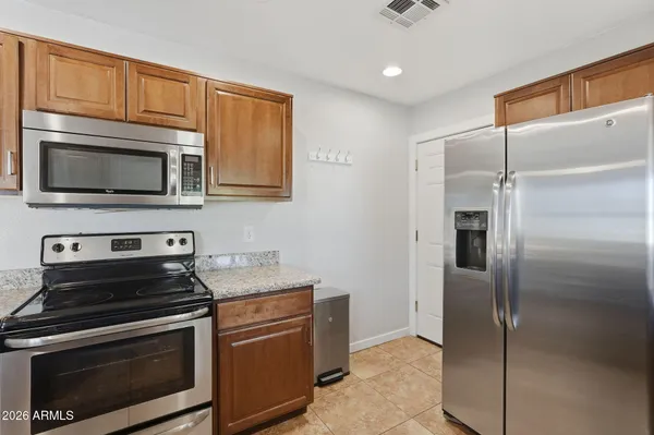 a kitchen with granite countertop wooden cabinets stainless steel appliances and a counter space