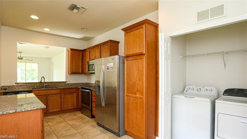 8482 Karina Court Naples, FL 34114 - Photo 12 of 40 a kitchen with a sink a refrigerator and cabinets