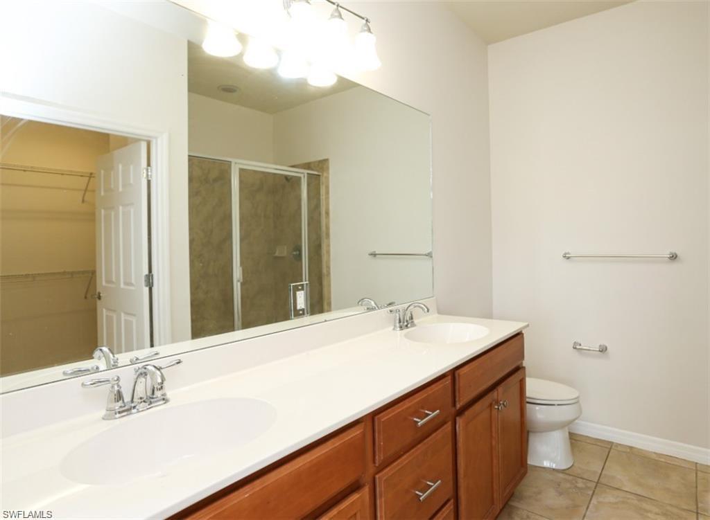 8482 Karina Court Naples, FL 34114 - Photo 16 of 40 a bathroom with a sink a toilet and mirror