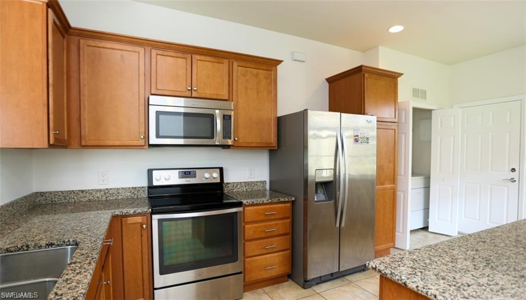 8482 Karina Court Naples, FL 34114 - Photo 9 of 40 a kitchen with stainless steel appliances granite countertop a refrigerator stove and microwave