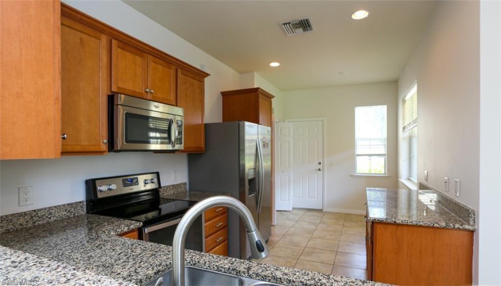 8482 Karina Court Naples, FL 34114 - Photo 10 of 40 a kitchen with granite countertop a refrigerator a stove a sink and a microwave