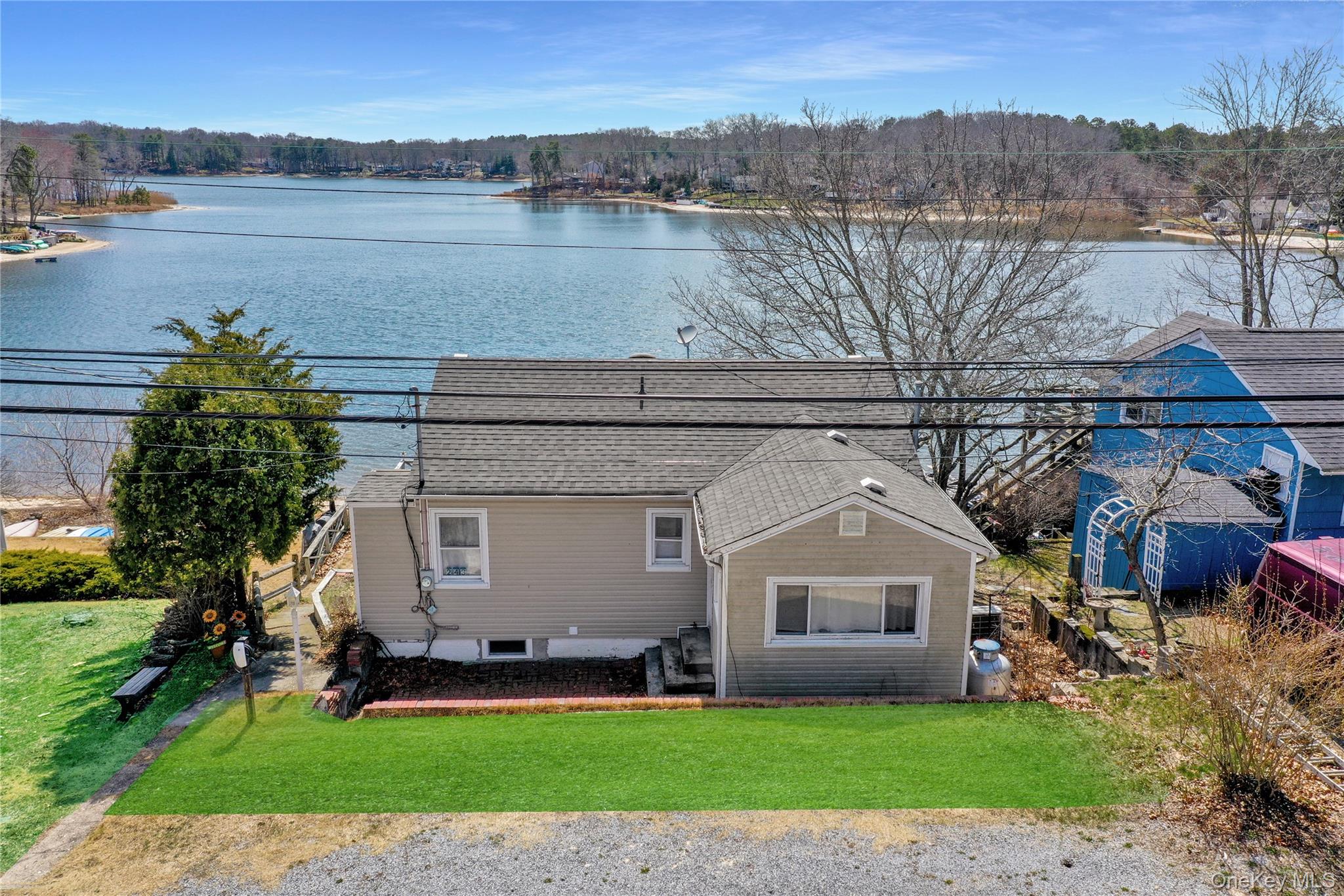 243 Lakeside Trail Ridge, NY 11961 - Photo 1 of 38 a front view of a house with a garden and lake view