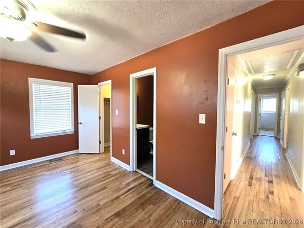 a view of a hallway with wooden floor and a bathroom