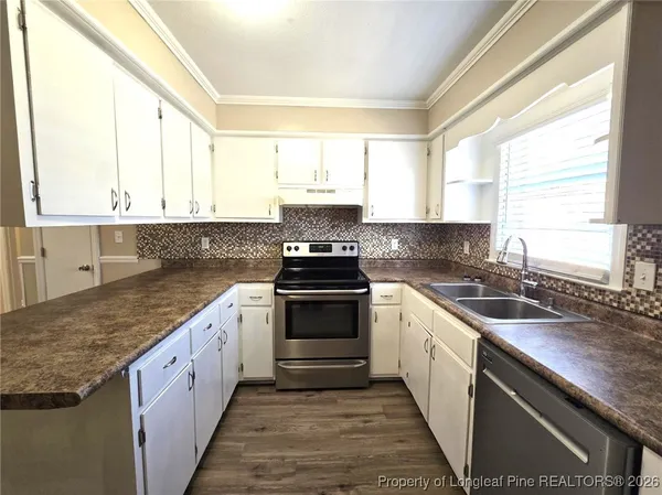 a white kitchen with granite countertop a sink and a window