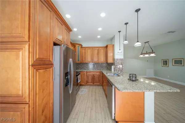 a kitchen with stainless steel appliances granite countertop a sink a stove and a refrigerator
