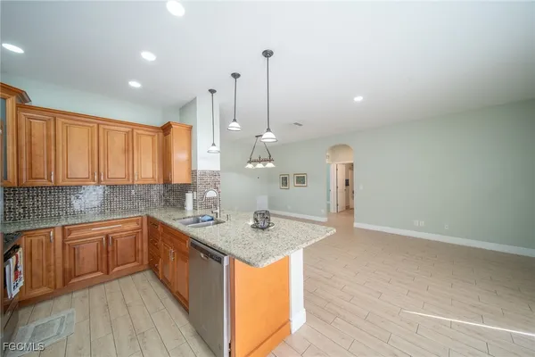 a kitchen with stainless steel appliances granite countertop a sink a stove and a wooden floors