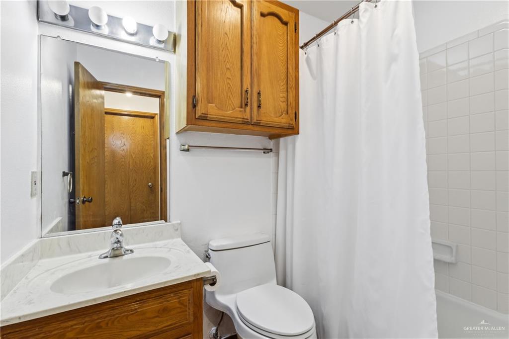 2312 Yarrow Street Mission, TX 78574 - Photo 12 of 20 a bathroom with a sink a toilet and shower curtain