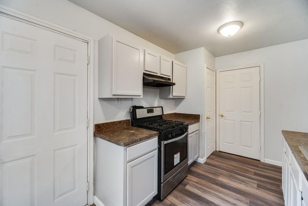 2526 Exeter Avenue Dallas, TX 75216 - Photo 12 of 19 Kitchen featuring white cabinetry, wood-finish flooring, a stainless steel range with overhead ventilation, and a built-in ceiling light fixture