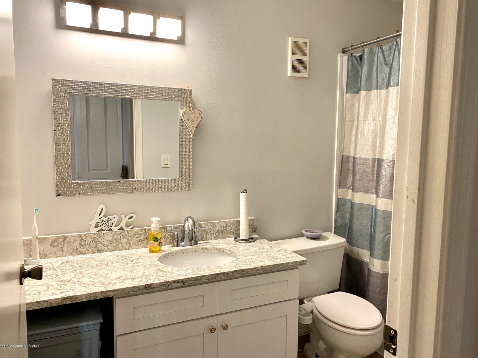 7667 North Wickham Road, Unit 214 Melbourne, FL 32940 - Photo 12 of 16 a bathroom with a granite countertop sink a toilet and a mirror