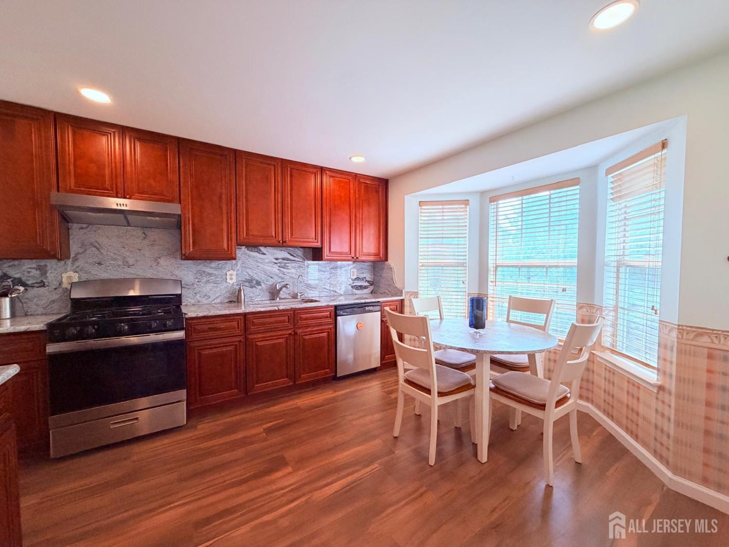918 Plymouth Road North Brunswick, NJ 08902 - Photo 12 of 30 a kitchen with stainless steel appliances granite countertop wooden floors and wooden cabinets