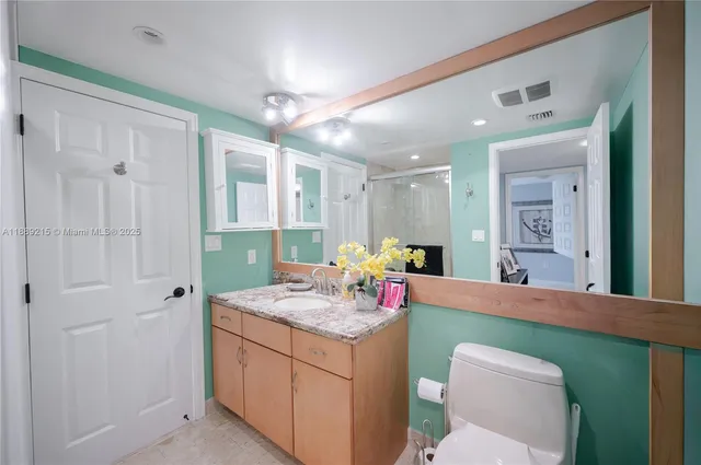 a bathroom with a granite countertop toilet sink and mirror