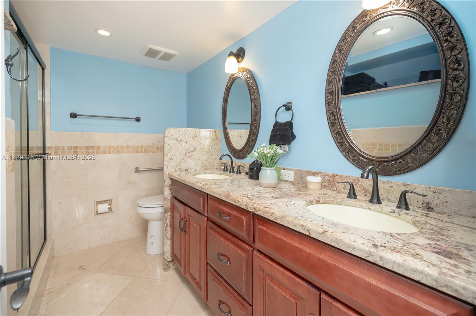 3 Grove Isle Drive, Unit C308 Miami, FL 33133 - Photo 16 of 54 a bathroom with a granite countertop toilet sink and mirror