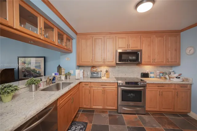 a kitchen with granite countertop a sink a stove top oven and cabinetry