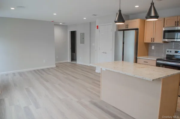 a large kitchen with stainless steel appliances kitchen island a large counter top a sink a stove and a refrigerator