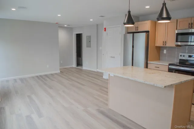 a large kitchen with stainless steel appliances kitchen island a large counter top a sink a stove and a refrigerator