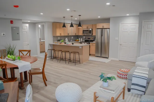 a kitchen with stainless steel appliances kitchen island granite countertop a refrigerator a stove a sink a dining table and chairs with wooden floor