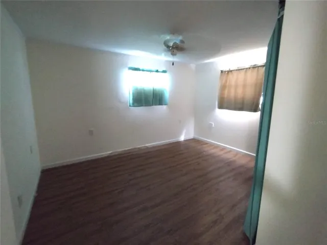 a view of an empty room with wooden floor and a bathroom