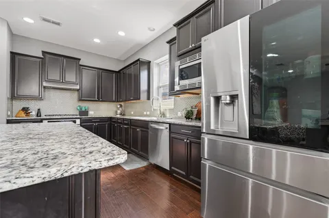 a kitchen with stainless steel appliances granite countertop a refrigerator a sink and a stove