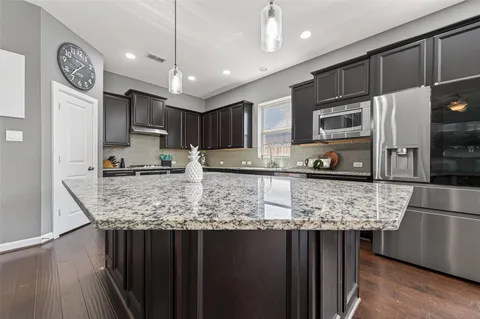 a kitchen with stainless steel appliances granite countertop a sink refrigerator and microwave