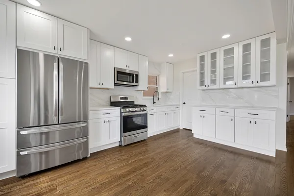 a kitchen with cabinets stainless steel appliances and wooden floor