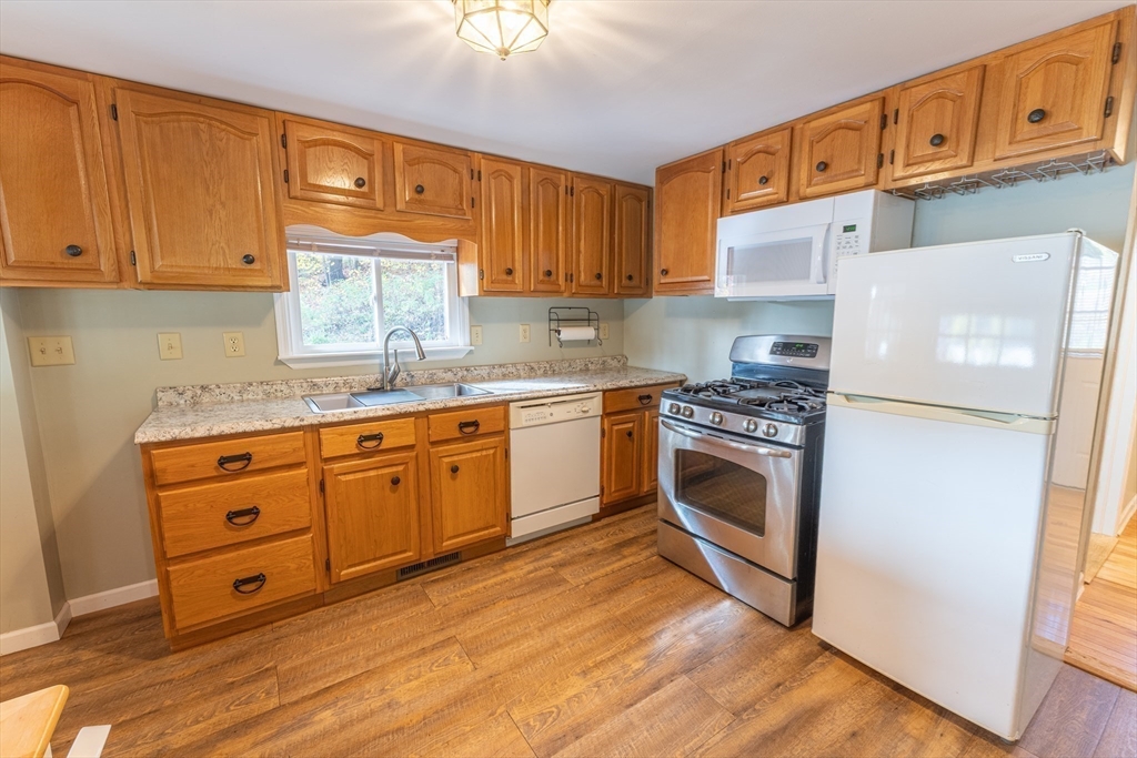 9 Chandler Road Holland, MA 01521 - Photo 11 of 42 a kitchen with granite countertop a stove top oven a sink dishwasher and white cabinets with wooden floor