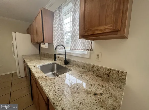 a kitchen with granite countertop a sink and a wooden cabinets