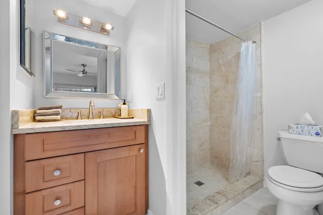 a bathroom with a granite countertop sink toilet and shower