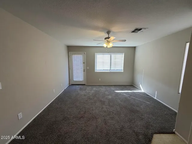 an empty room with windows and chandelier fan