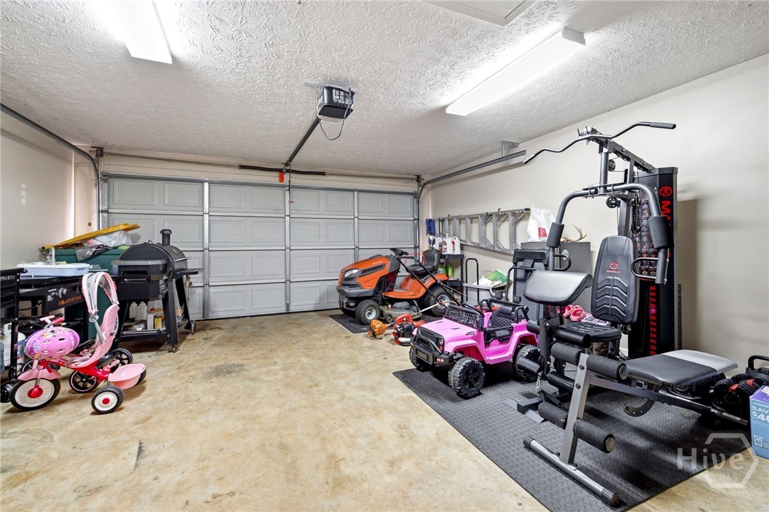 121 Crestview Drive Carnesville, GA 30521 - Photo 23 of 28 Spacious two-car garage featuring a sectional overhead door with an automatic opener, interior fluorescent lighting, painted walls, and a concrete floor