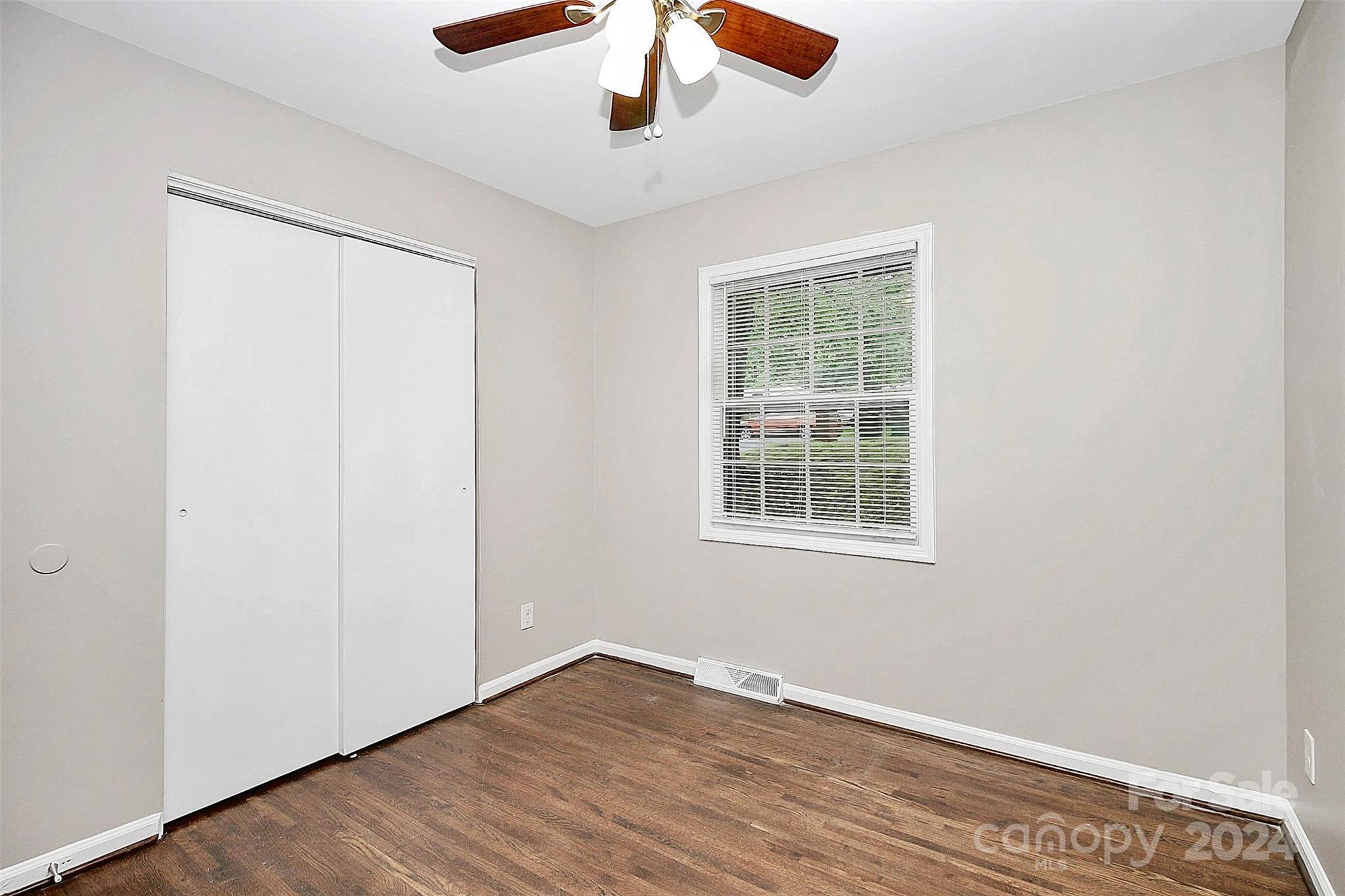 1120 Claremont Road Charlotte, NC 28214 - Photo 27 of 37 an empty room with wooden floor chandelier fan and windows
