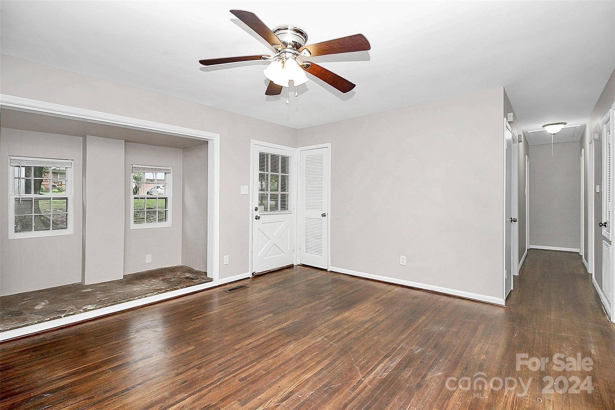 1120 Claremont Road Charlotte, NC 28214 - Photo 5 of 37 an empty room with wooden floor chandelier fan and windows