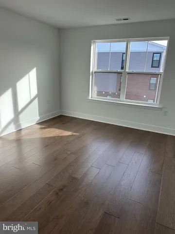 an empty room with wooden floor cabinets and windows