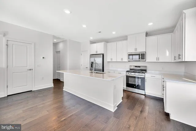 a kitchen with wooden floors white cabinets and stainless steel appliances