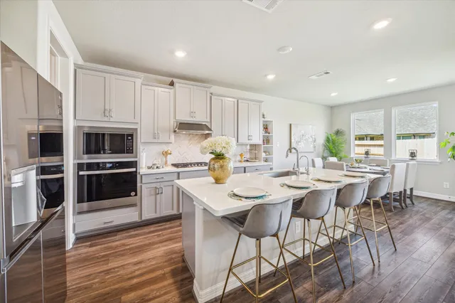 a kitchen with stainless steel appliances kitchen island granite countertop a stove a sink a microwave and a refrigerator