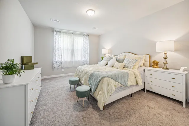 a bedroom with a bed and a lamp on dresser